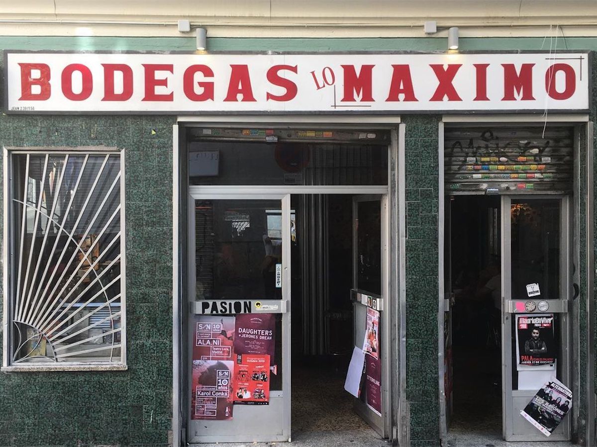 Exterior de un pequeño bar con un cartel rojo y blanco en el que se lee Bodegas Lo Máximo